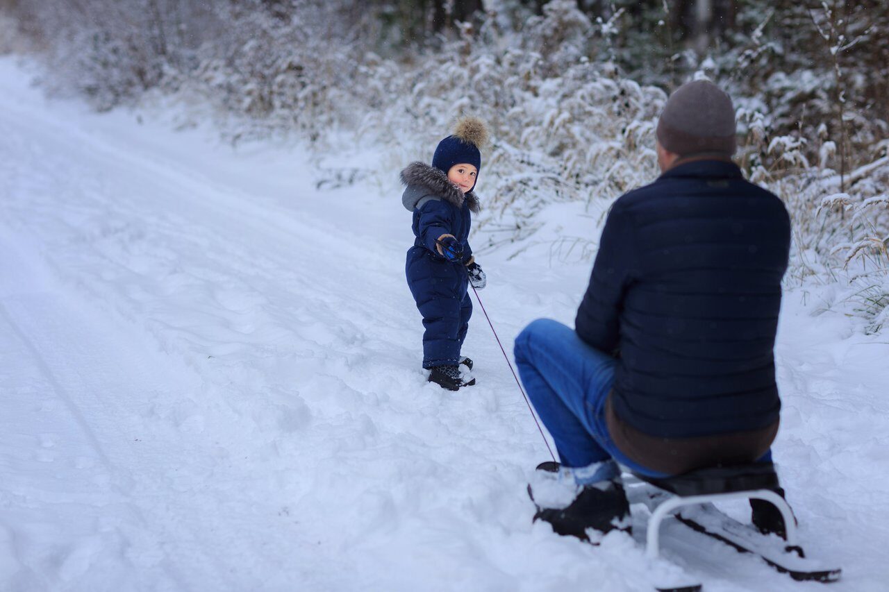 Маленький мальчик тащит папу из тц. Папа катает ребенка на санках. Папа везет ребенка на санках. Ребенок на снегокате. Мальчик на санках папу.